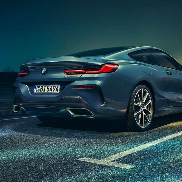 BMW Série 8 Coupé, vue de trois quarts arrière. BMW Série 8 Coupé, vue de trois quarts arrière, à l’arrêt devant un décor nocturne.