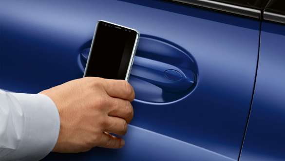 BMW Digital Key la nouvelle BMW Série 8 Coupé G15 M Portimao Blau metallic LCI restylage 2022 main qui tient un smartphone devant la porte de la voiture