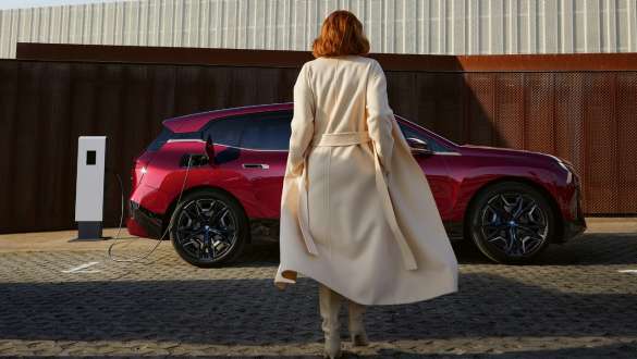 BMW iX M60 i20 2022 SUV électrique Connected Charging Femme devant une BMW iX