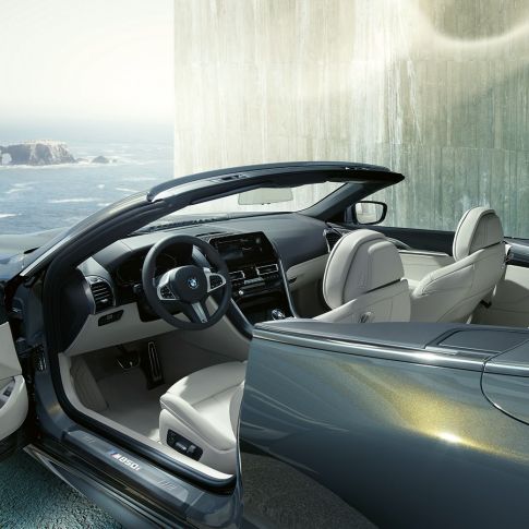 BMW M850i xDrive Cabrio, habitacle. BMW M850i xDrive Cabrio in Dravitgrau metallic avec capote ouverte, habitacle avec volant M en cuir et garnissage BMW Individual en cuir Merino Elfenbeinweiß.