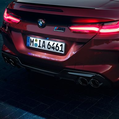 BMW M8 Competition Cabrio, vue en gros plan de l’arrière. BMW M8 Competition Cabrio en Motegi Rot metallic, vue en gros plan de l’arrière avec feux arrière à LED et badge M8 Competition.
