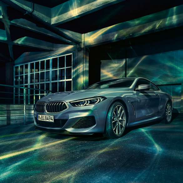 BMW M850i xDrive Coupé, vue de trois quarts avant. BMW M850i xDrive Coupé en Barcelona Blau metallic, vue de trois quarts avant à l’arrêt devant un immeuble.