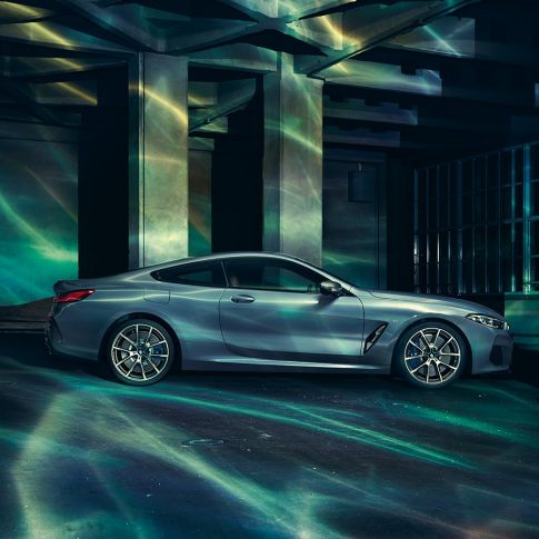BMW M850i xDrive Coupé, vue de profil. BMW M850i xDrive Coupé en Barcelona Blau metallic, vue de profil, à l’arrêt devant un immeuble.