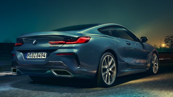 BMW M850i xDrive Coupé, vue arrière. BMW M850i xDrive Coupé en Barcelona Blau metallic en marche, vue nocturne arrière.