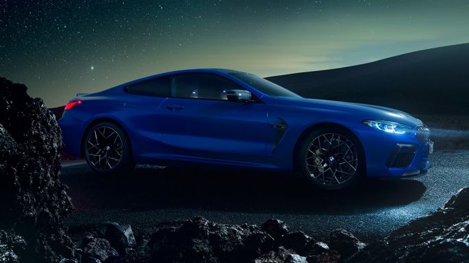 BMW M8 Competition Coupé, vue de trois quarts de profil. BMW M8 Competition Coupé en Marina Bay Blau metallic, vue de trois quarts de profil à l’arrêt, de nuit.