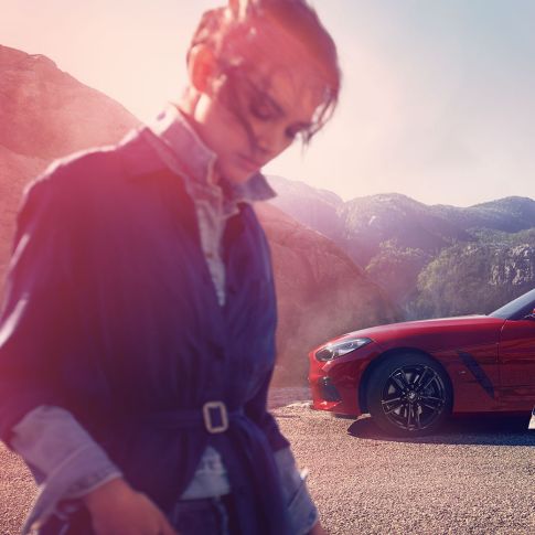La BMW Z4 Roadster devant un paysage de montagnes Homme et femme devant la BMW Z4 Roadster avec à l’arrière-plan un paysage de montagnes