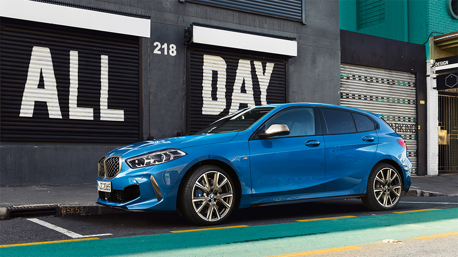 La BMW Série 1 M135i F40 en Misano Blau metallic, vue de profil en stationnement.