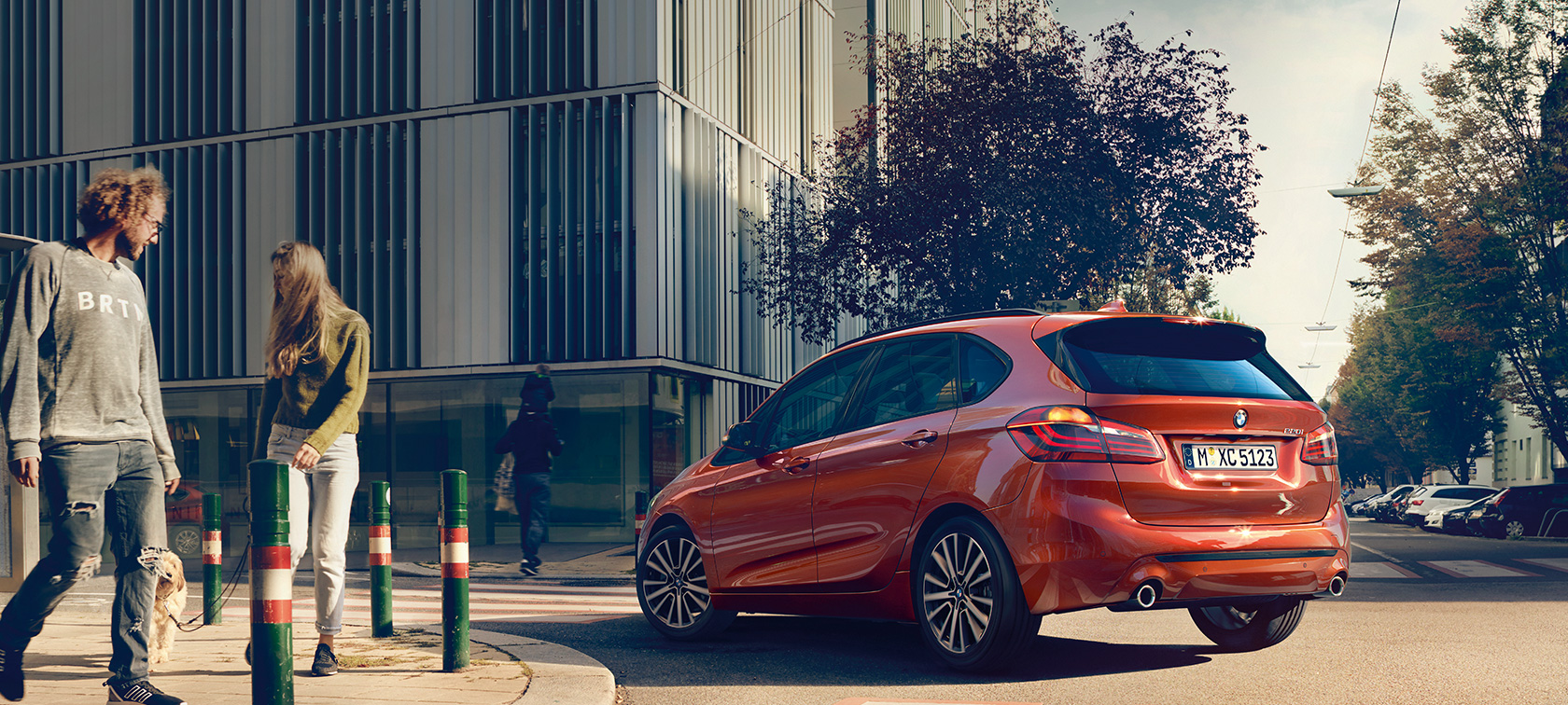 Vue de trois quarts arrière de la BMW Série 2 Active Tourer 220i BMW Série 2 Active Tourer 220i F45 restylage 2018 Sunset Orange metallic, vue de trois quarts arrière, en mouvement sur la route