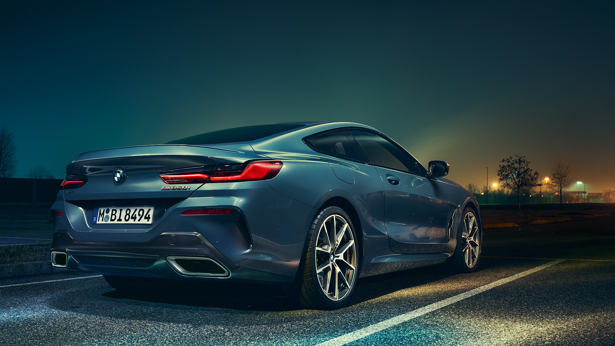 BMW Série 8 Coupé, vue de trois quarts arrière. BMW Série 8 Coupé, vue de trois quarts arrière, à l’arrêt devant un décor nocturne.