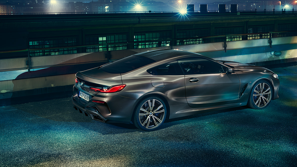 Vue latérale de la BMW Série 8 Coupé à l’arrêt. La BMW Série 8 Coupé avec équipement BMW Individual, photographiée de profil à l'arrêt dans un décor urbain de nuit.
