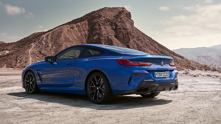 La nouvelle BMW Série 8 Coupé Pack M Sport G15 LCI restylage 2022 M Portimao Blau metallic vue de trois quarts arrière face à des rochers