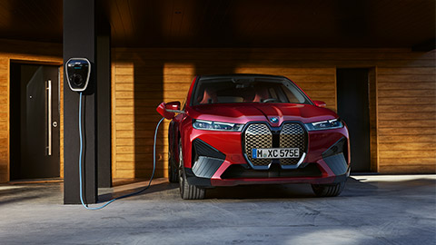 Modèles BMW i Vue avant BMW iX à l’arrêt sur une borne de recharge