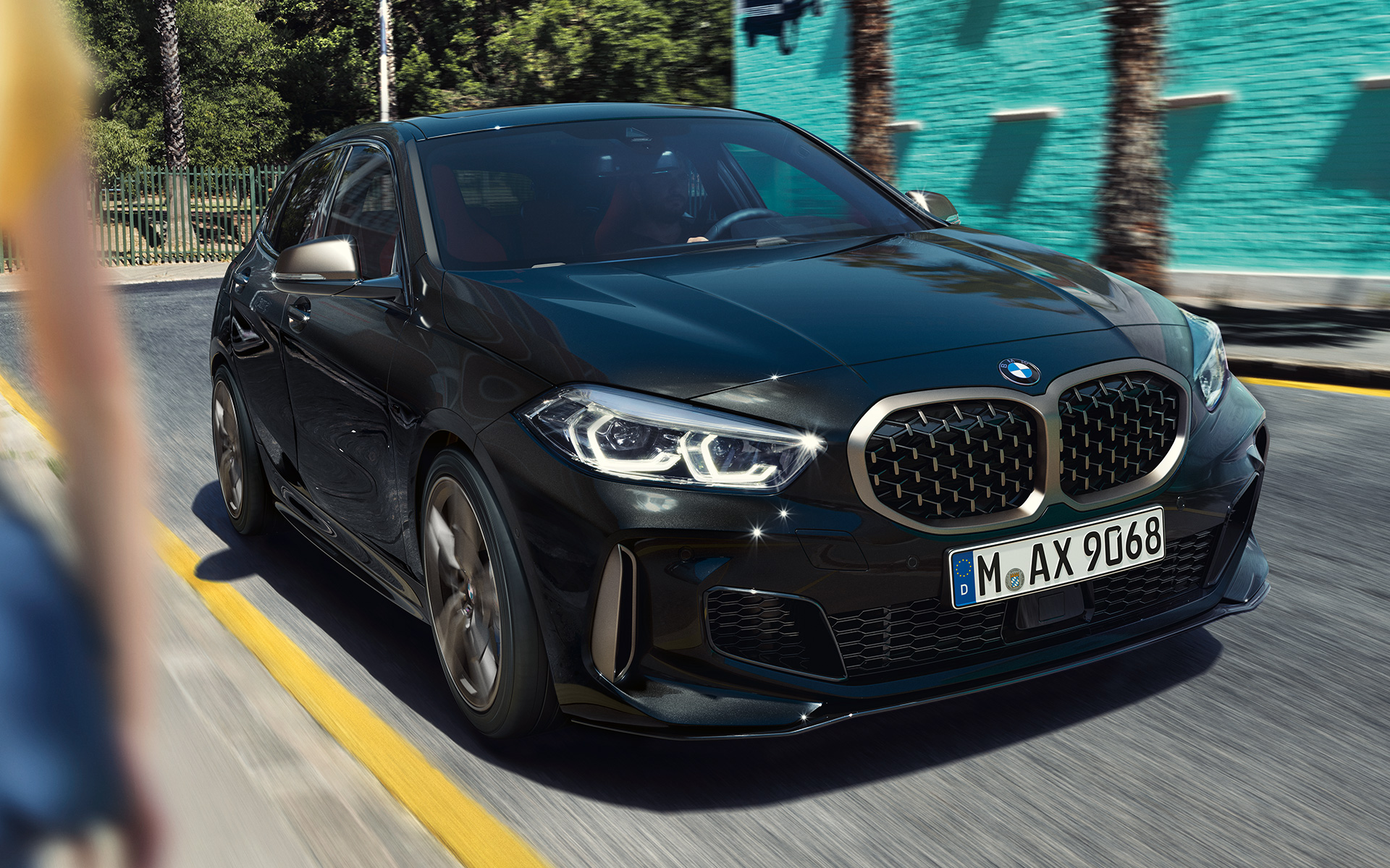BMW M135i xDrive (F40) en Saphirschwarz metallic, vue de trois quarts avant en mouvement