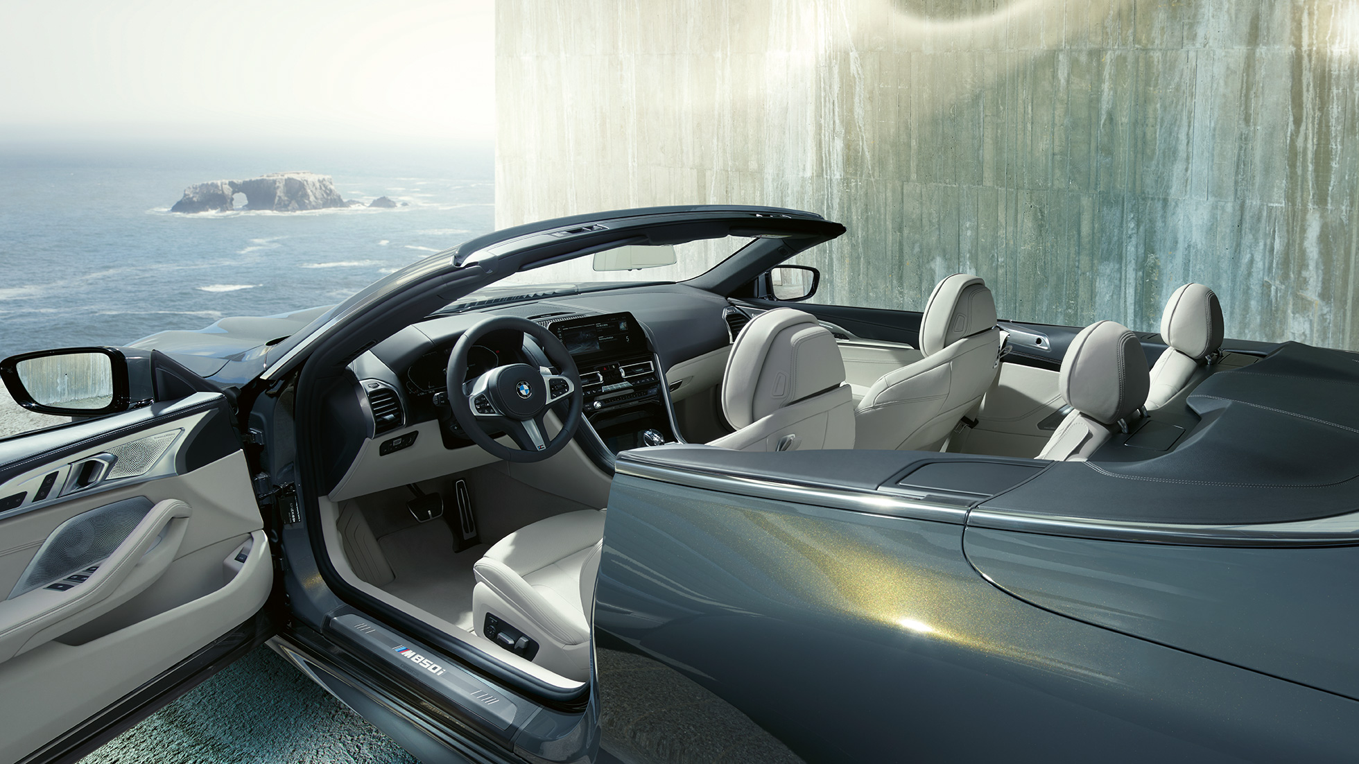 BMW M850i xDrive Cabrio, habitacle. BMW M850i xDrive Cabrio in Dravitgrau metallic avec capote ouverte, habitacle avec volant M en cuir et garnissage BMW Individual en cuir Merino Elfenbeinweiß.