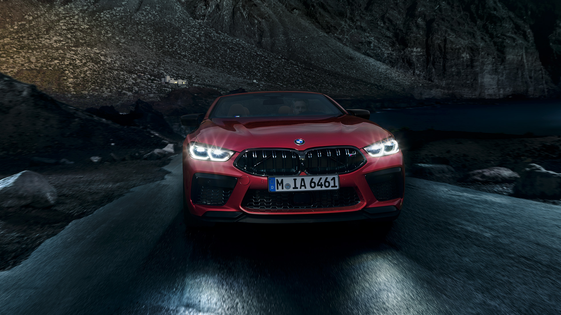 BMW M8 Competition Cabrio, vue avant. BMW M8 Competition Cabrio en Motegi Rot metallic avec phares allumés, vue avant, en conduite de nuit.