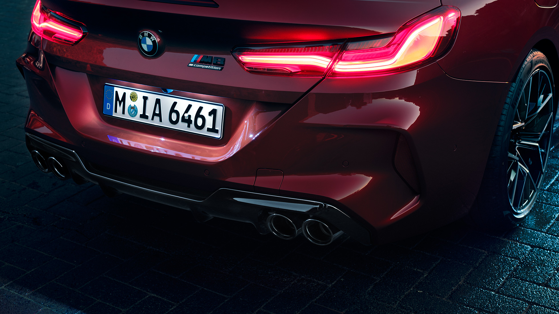 BMW M8 Competition Cabrio, vue en gros plan de l’arrière. BMW M8 Competition Cabrio en Motegi Rot metallic, vue en gros plan de l’arrière avec feux arrière à LED et badge M8 Competition.