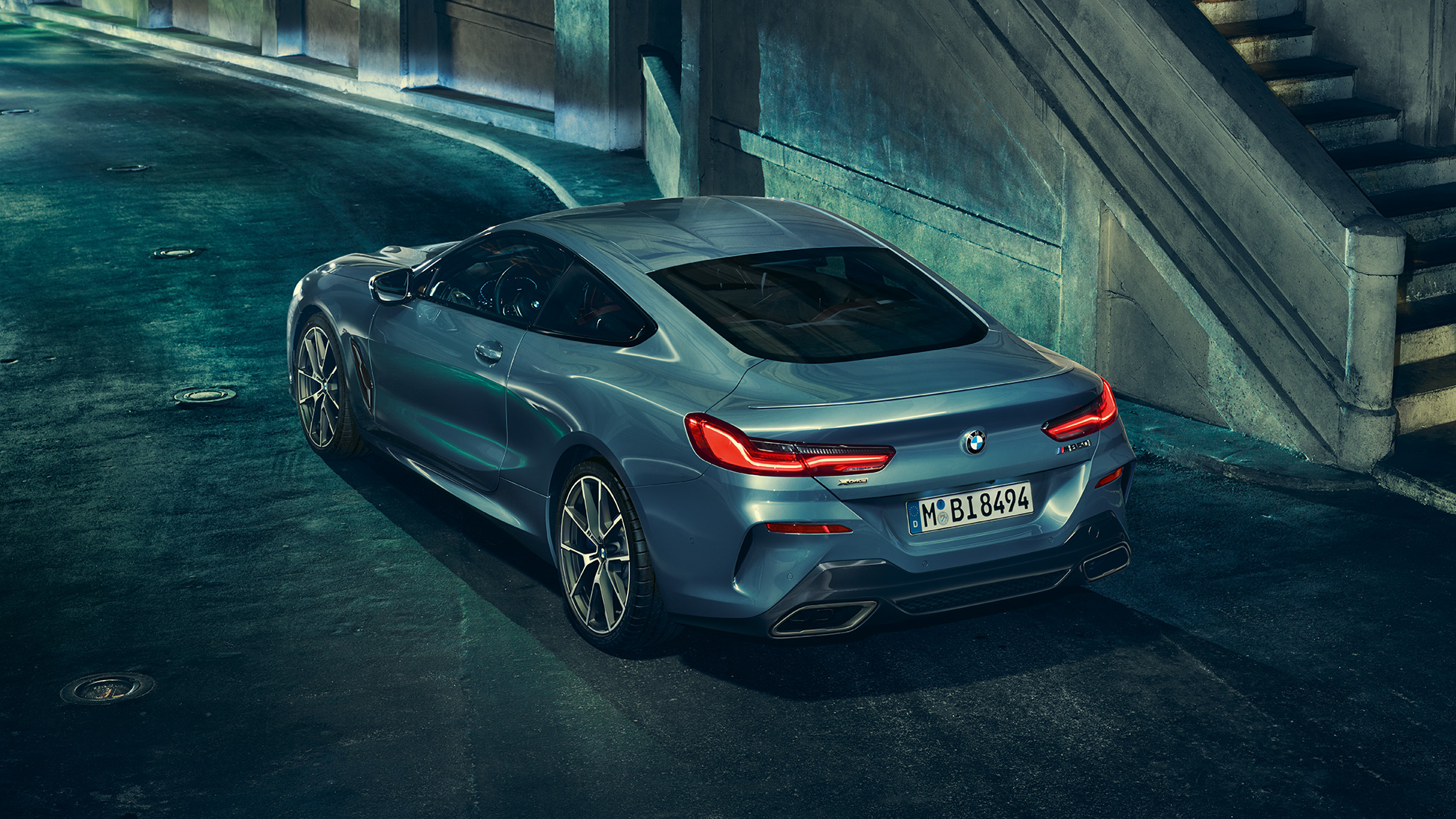 BMW M850i xDrive Coupé, vue de trois quarts arrière gauche. BMW M850i xDrive Coupé en Barcelona Blau metallic, vue de trois quarts arrière gauche, à l’arrêt, de nuit.