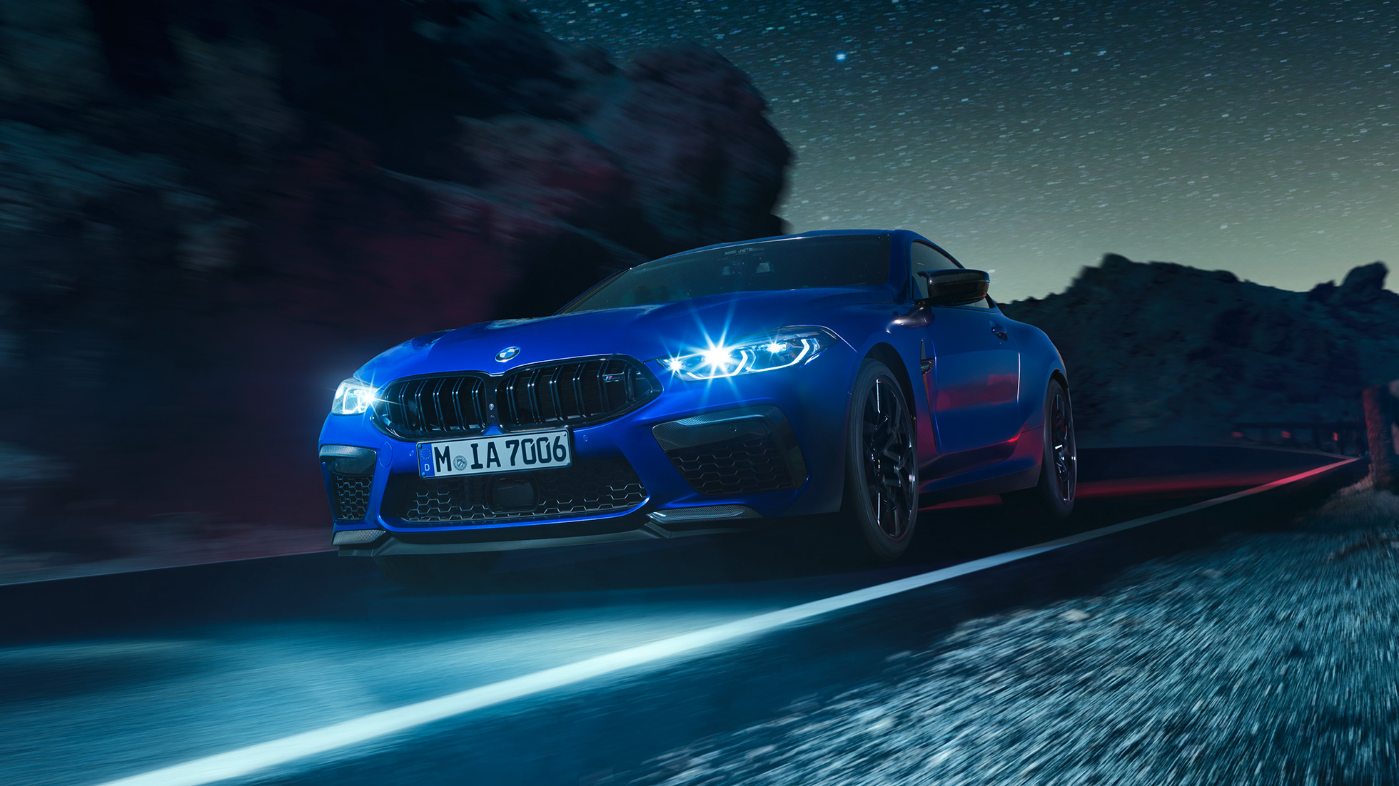 BMW M8 Competition Coupé en marche, vue de trois quarts avant. BMW M8 Competition Coupé en Marina Bay Blau metallic avec phares LED allumés, vue de trois quarts avant en marche, de nuit.