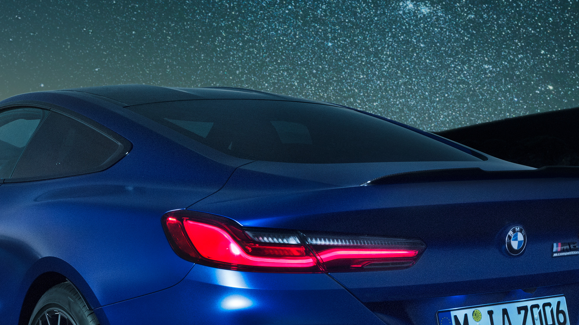 Becquet M arrière BMW M8 Competition Coupé en Marina Bay Blau metallic, vue en gros plan de la carrure de nuit, avec diffuseur M en Carbon Schwarz.