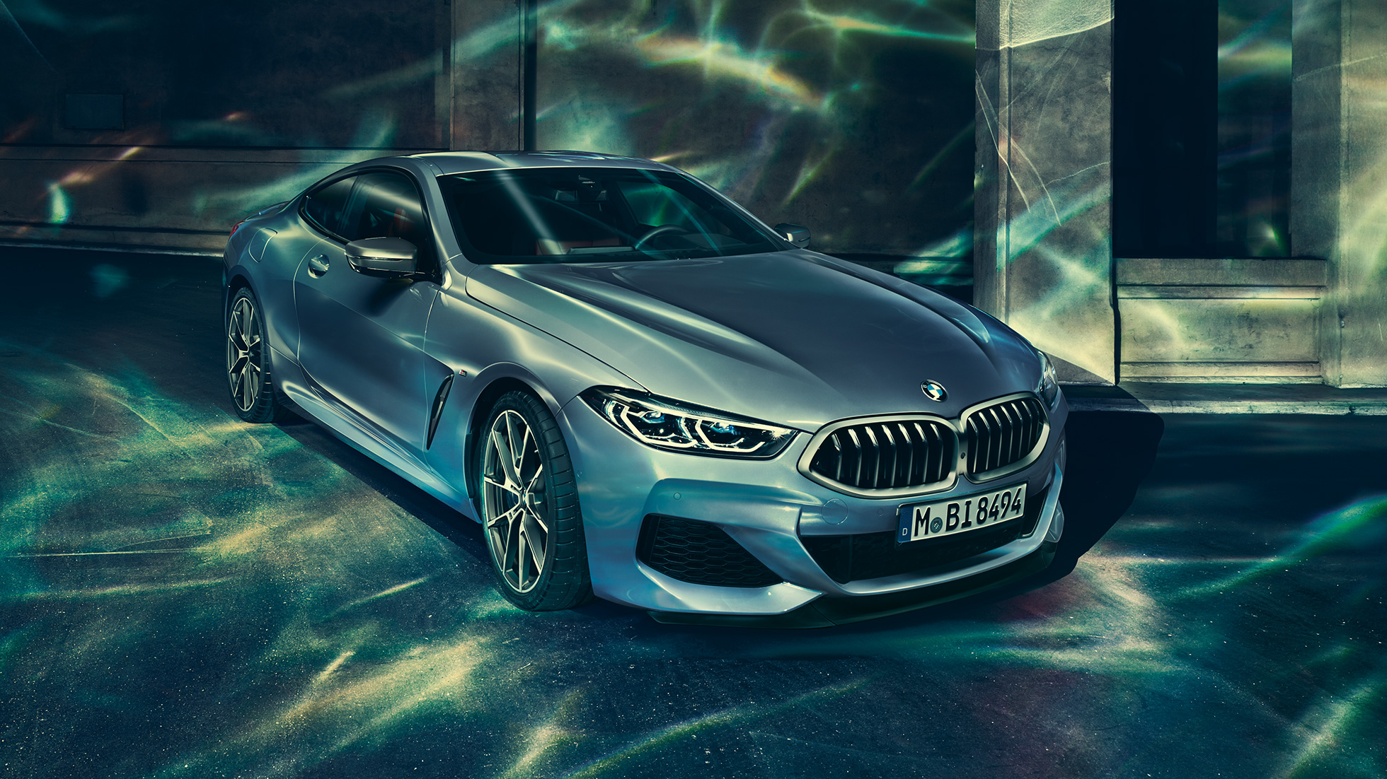 BMW M850i xDrive Coupé, vue de trois quarts avant gauche. BMW M850i xDrive Coupé en Barcelona Blau metallic, vue de trois quarts avant gauche, à l’arrêt devant un immeuble.