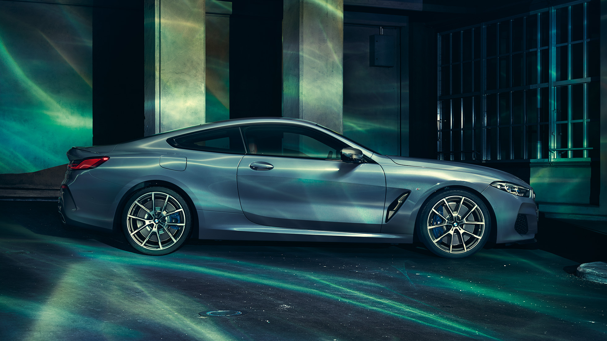 BMW M850i xDrive Coupé, vue de profil. BMW M850i xDrive Coupé en Barcelona Blau metallic, vue de profil, à l’arrêt devant un immeuble.