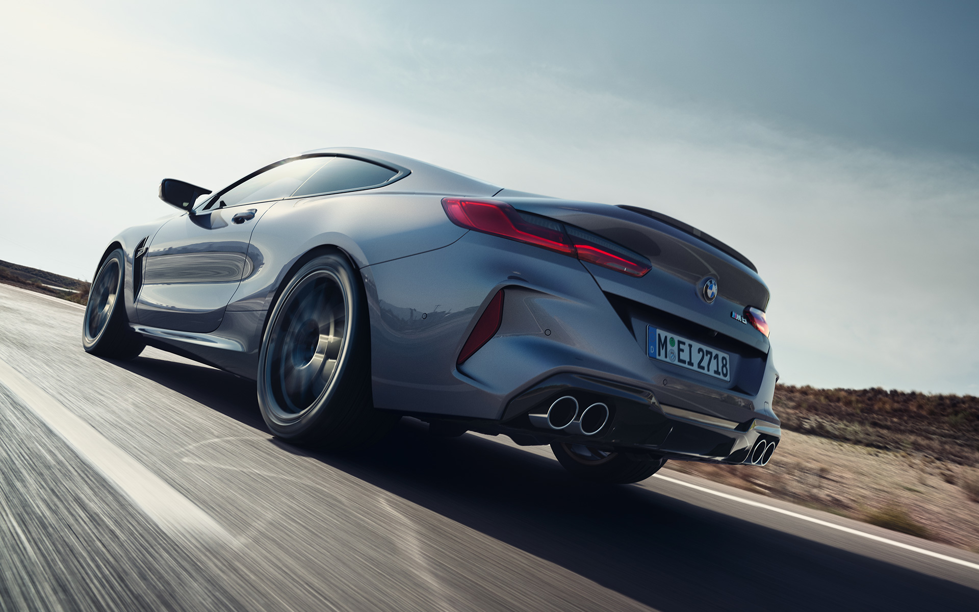 BMW M8 coupe F92 LCI facelift 2022 Skyscraper grey metallic three-quarter rear view driving on a highway low angle shot
