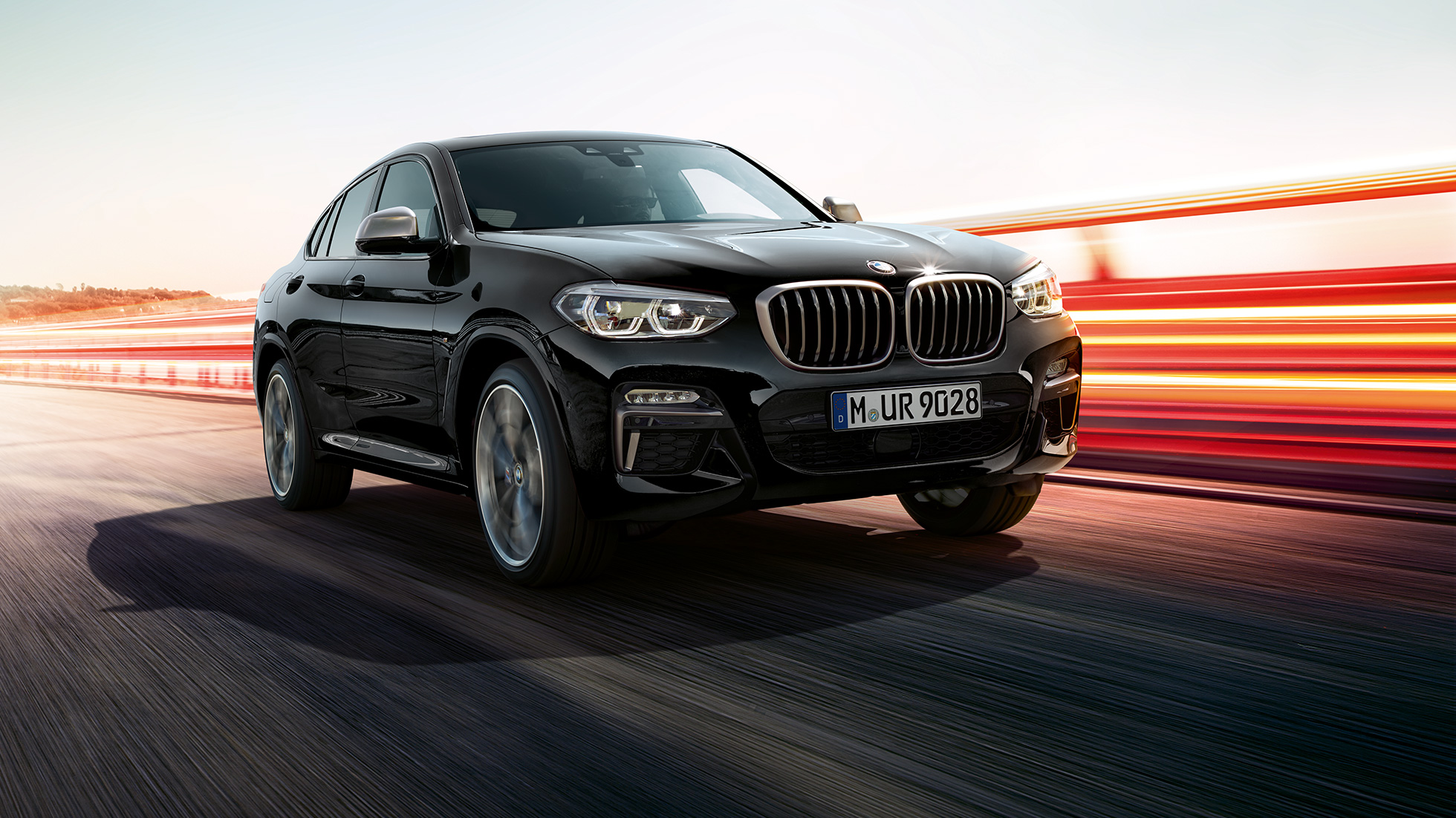BMW X4 M40i et BMW X4 M40d, vue de trois quarts avant. Extérieur des BMW X4 M40i et BMW X4 M40d en Saphierschwarz metallic, vue de trois quarts avant gauche avec bandes lumineuses.