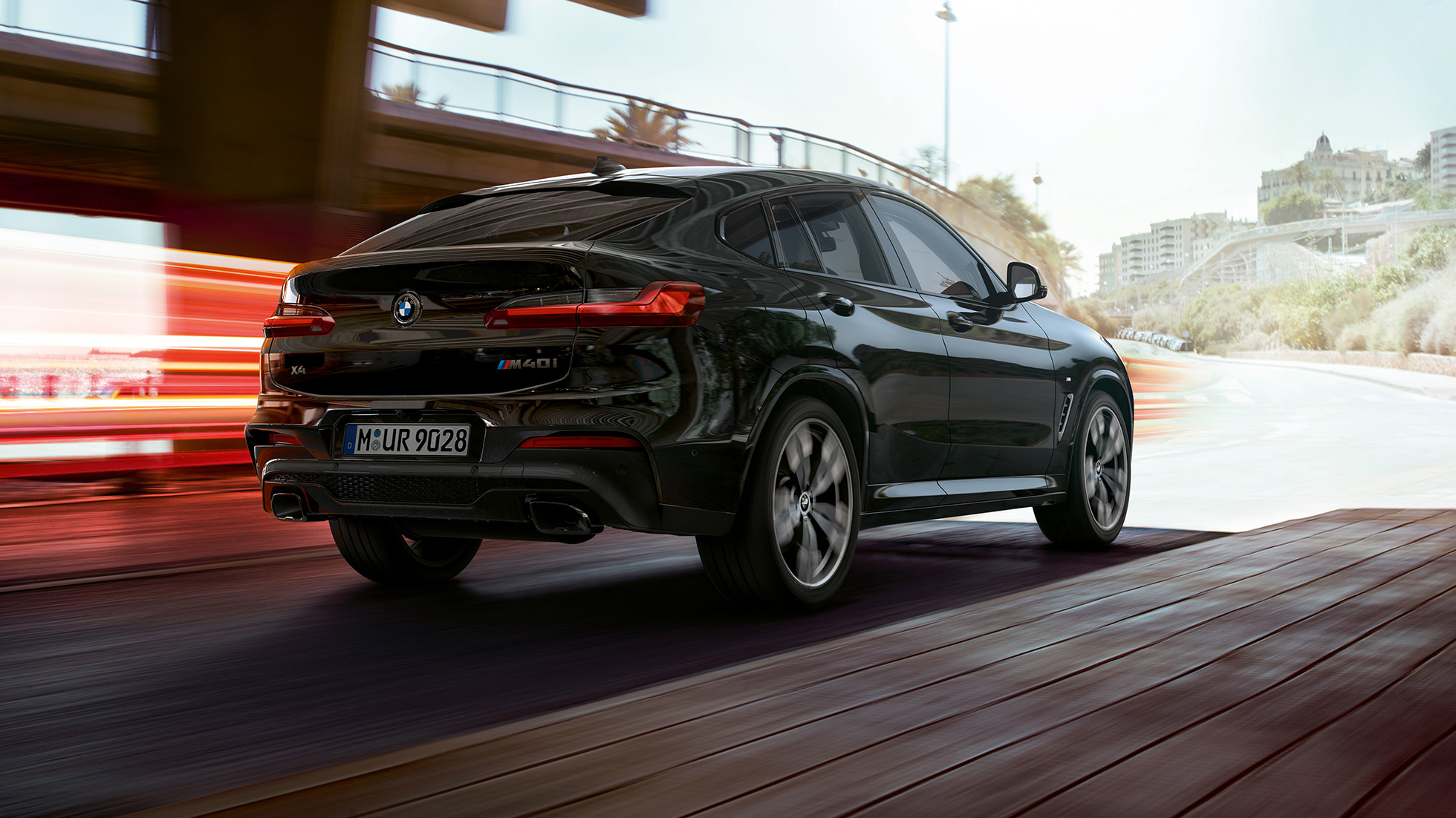BMW X4 M40i, vue de trois quarts arrière. Extérieur de la BMW X4 M40i en Saphierschwarz metallic, vue de trois quarts arrière droite avec bandes lumineuses.
