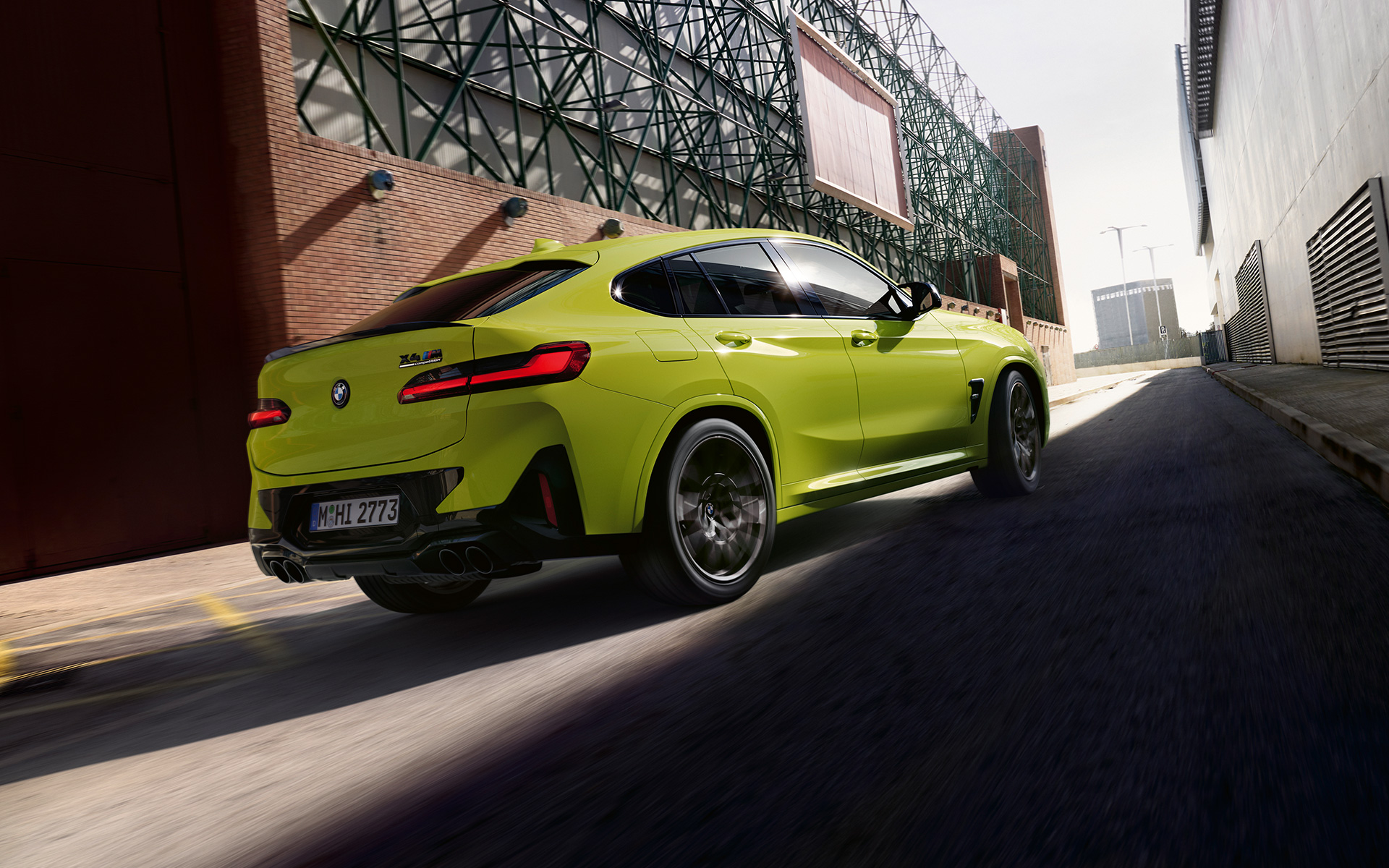 BMW X4 M Competition F98 LCI Facelift 2021 Sao Paulo Gelb vue de trois quarts arrière roulant entre des bâtiments d’usine