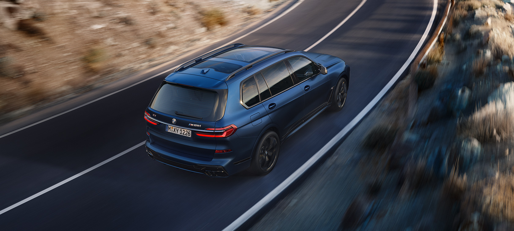 BMW X7 M60i xDrive G07 LCI Frozen Marina Bay Blue vue de trois quarts arrière en mouvement vue en plongée BMW X7 M60i xDrive G07 LCI Frozen Marina Bay Blue vue de trois quarts arrière en mouvement sur la route
