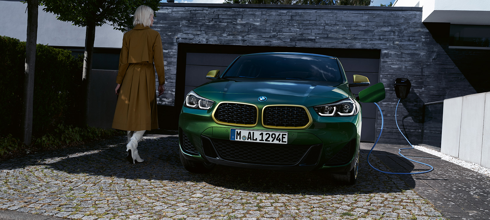 Vue avant en recharge avec modèle à gauche BMW X2 F39 Sanremo Green metallic