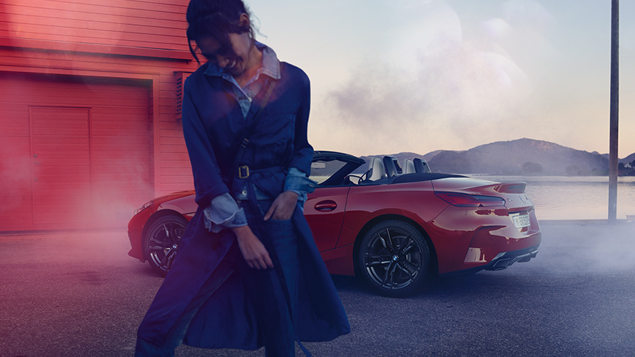 BMW Z4 M40i Roadster G29 avec capote ouverte BMW Z4 M40i Roadster G29 vue de trois quarts arrière avec capote ouverte et femme en avant plan