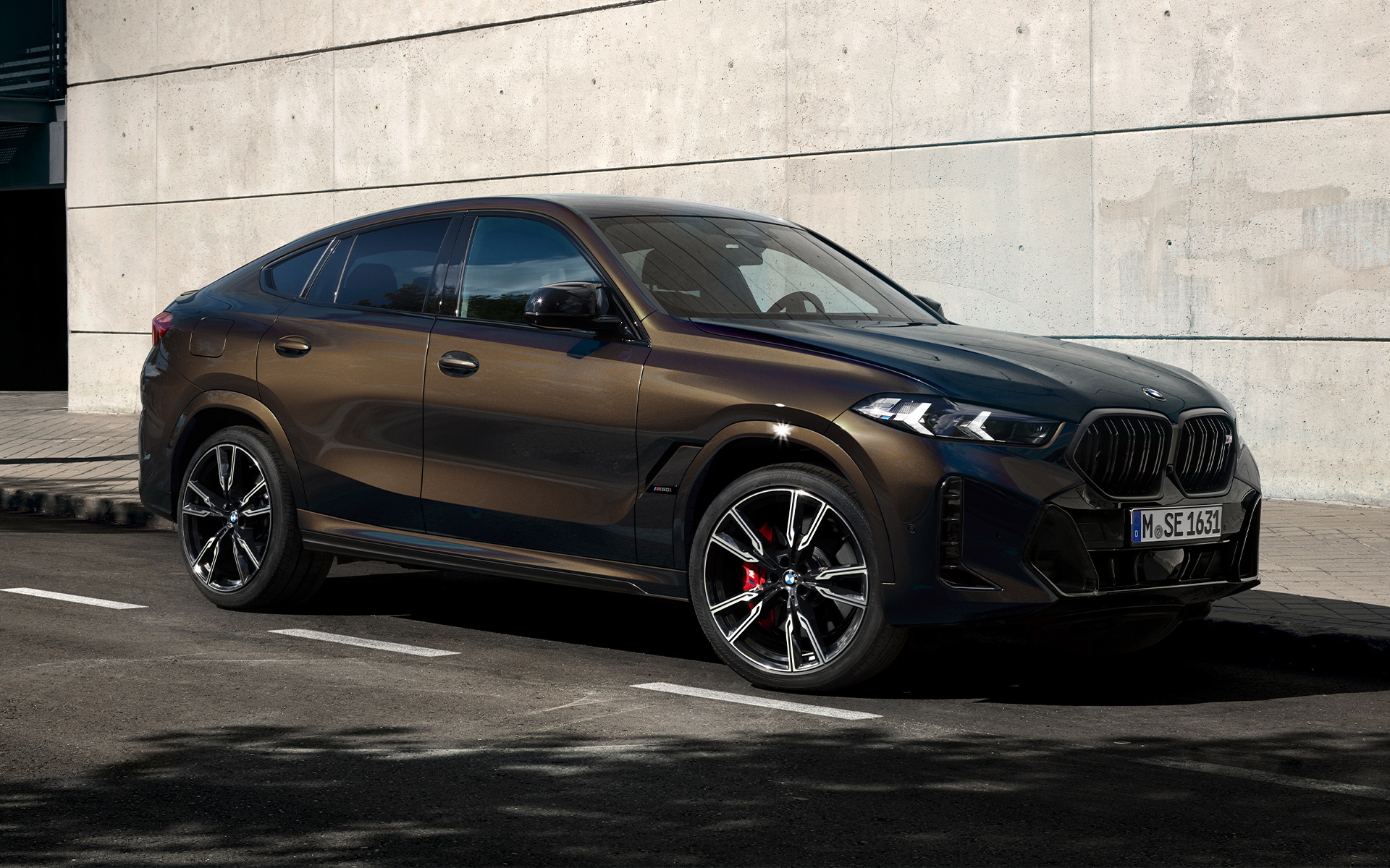 BMW X6 M60i G06 en Pyritbraun metallic BMW X6 M60i G06 en BMW Individual Pyritbraun metallic, 2/3 vue de profil à l’arrêt sur une place de stationnement