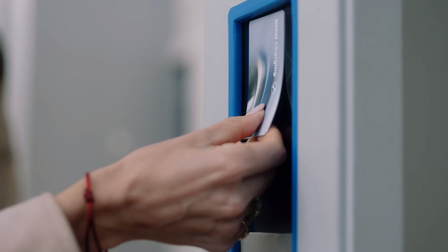 Personne tenant une BMW Charging Card à une station de recharge publique