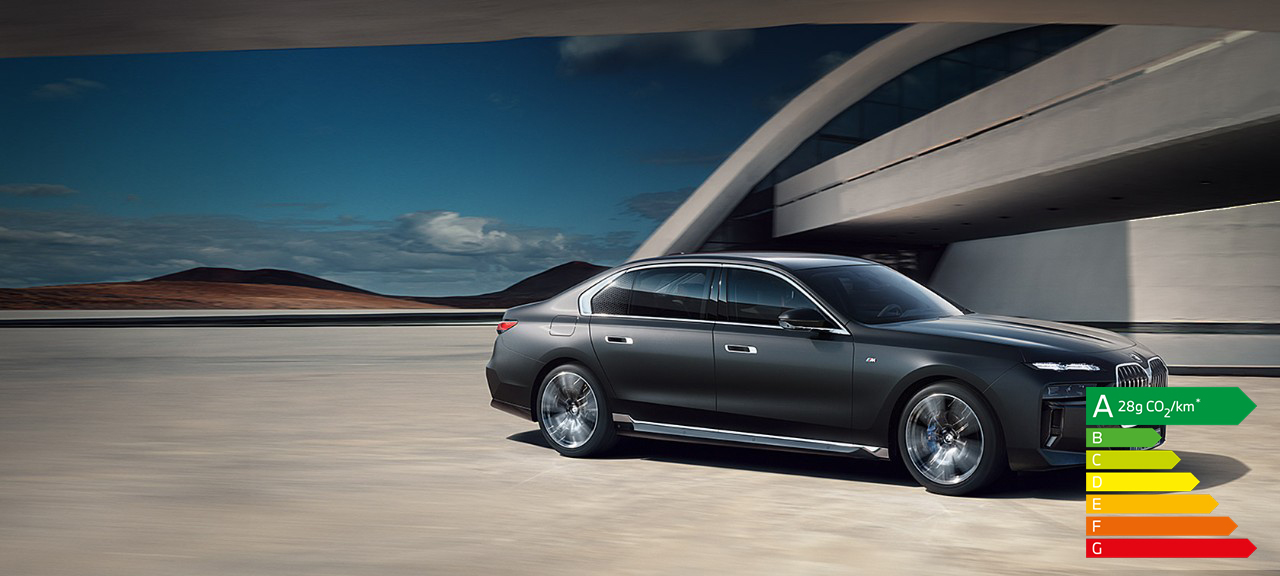 BMW Série 7 Berline G70 ICE kit M Sport Frozen Deep grey metallic vue ¾ face à l’arrêt devant un bâtiment
