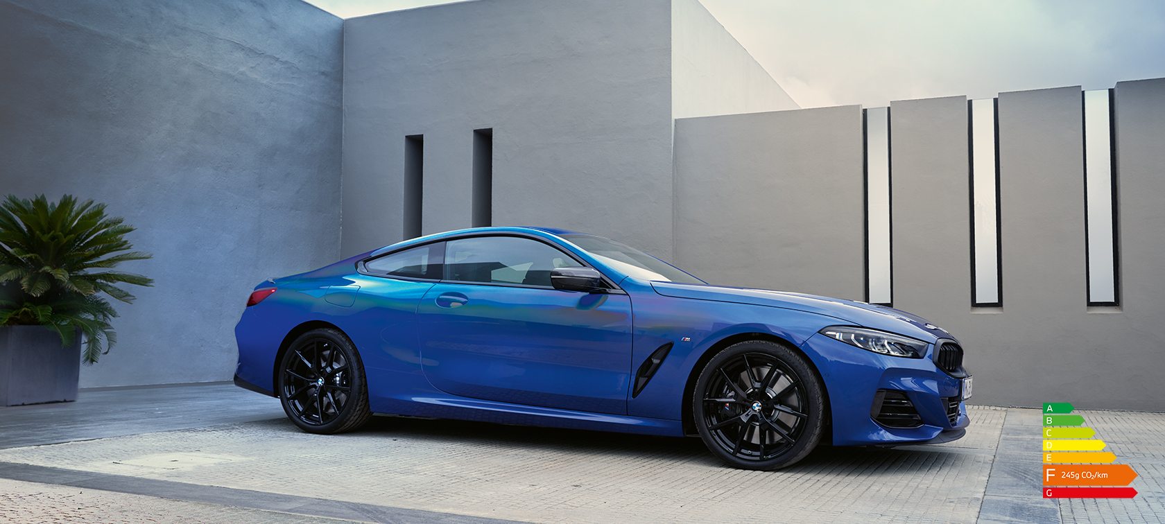 La nouvelle BMW Série 8 Coupé G15 LCI restylage 2022 M Portimao Blau metallic vue de profil en stationnement devant un mur